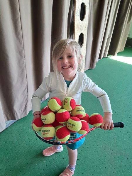 Little Girl With Tennis Balls On Her Racket